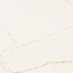 White marble surface with subtle gold veining, creating an elegant pattern. The background is plain, highlighting the natural artistry of the marble's texture and color variations.