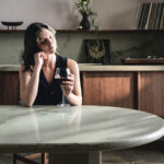 Caesarstone 8477 Ocean Sage fusion kitchen with a woman drinking wine