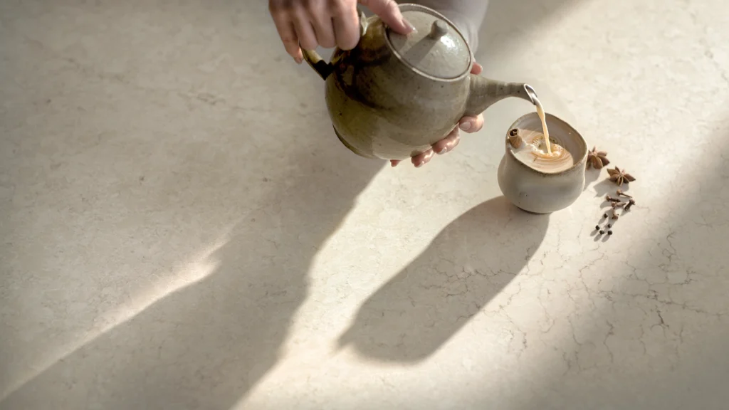 Caesarstone ICON 8252_Sedara white surface with hand pouring tea from a teapot into a cup beside star anise and cloves.